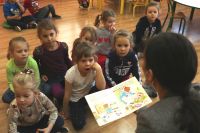 Na zdjęciu grupa dzieci słucha czytanej bajki