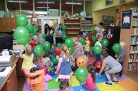 Gromada dzieci w bibliotece bawiąca się zielonymi balonikami