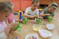 Dzieci przedszkolne przy stoliku z materiałami plastycznymi