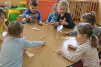 Grupa dzieci przy stoliku z papierowymi króliczkami