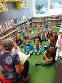 Grupa dzieci podczas głośnego czytania w bibliotece