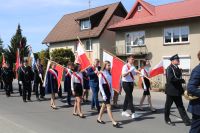 Uczniowie z Szkoły Podstawowej z masztem Flagi Polski podczas marszu