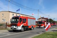 Pojazdy Ochotniczej Straży Pożarnej na tle Urzędu Gminy Wielgie podczas marszu