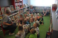 Zdjęcie grupowe dzieci podczas czytania książki w bibliotece