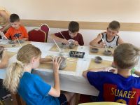 Dzieci modelujące z gliny podstawę do świnki skarbonki