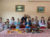 Zdjęcie grupowe dzieci uczestniczących w warsztatach budowania makiety z klocków lego wraz z wykonanymi organizerami.