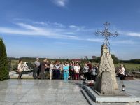 Uczestnicy wycieczki przed tablicą upamiętniającą powstańców na cmentarzu w Ligowie.