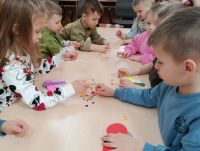 Dzieci przedszkolne wykonują motyla z papierowych elementów