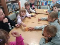 Dzieci przy stolikach podczas zajęć w bibliotece