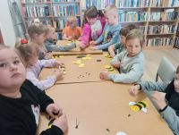 Dzieci przy stolikach podczas zajęć w bibliotece