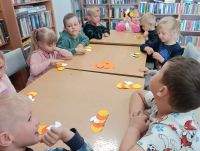 Dzieci przy stolikach podczas zajęć w bibliotece