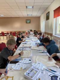 Uczestnicy z Klubu Młodzieżowego w Wielgiem 1 malujący materiałowe worki w loga swoich ulubionych klubów piłkarskich.