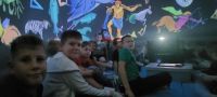 Dzieci z klubów młodzieżowych w mobilnym planetarium podczas warsztatów naukowych z astronomii.