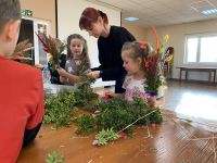 Uczestnicy zajęć tworzący własne palmy wielkanocne.